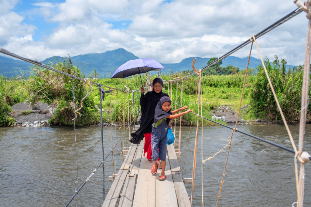 Homebound, mother and child  cross the hanging bridge after shopping in Butig’s central market.
